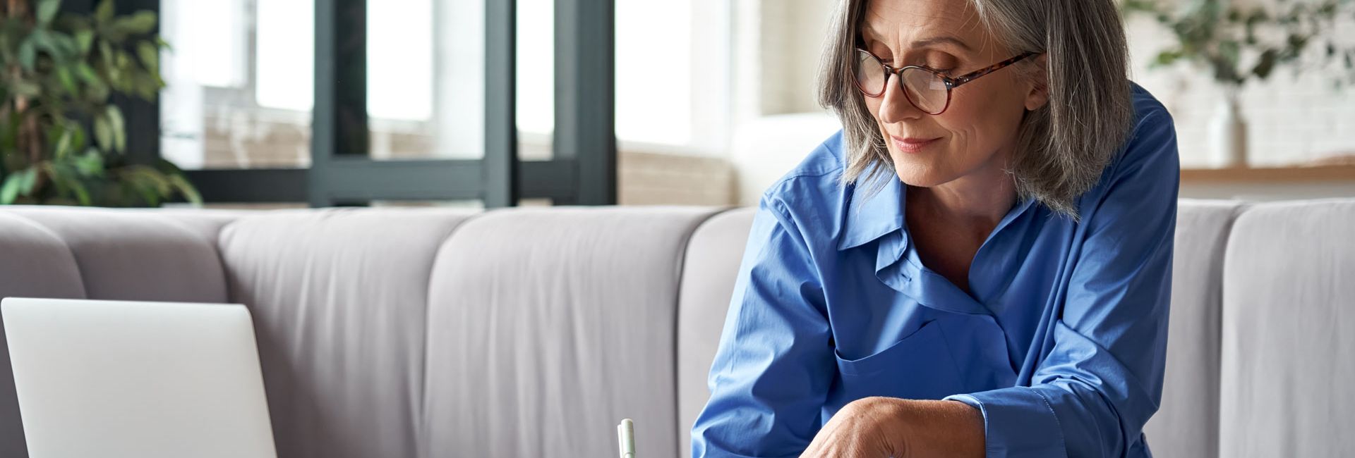 Ältere Dame benutzt einen Laptop, schreibt eine E-Mail