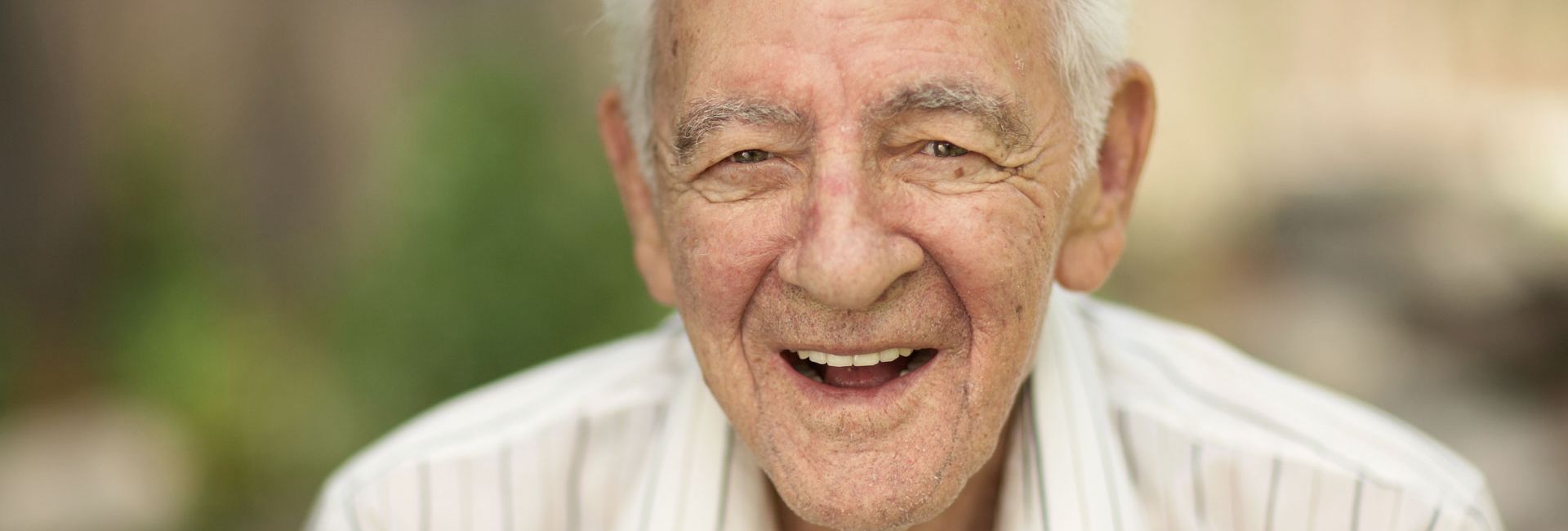 Älterer Herr freut sich und lacht, fühlt sich gut gepflegt und versorgt